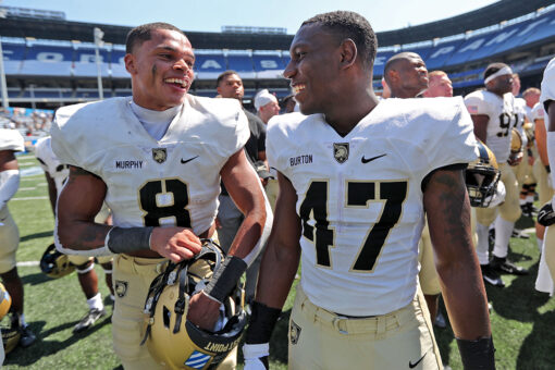 Army football players run out on field carrying American flags