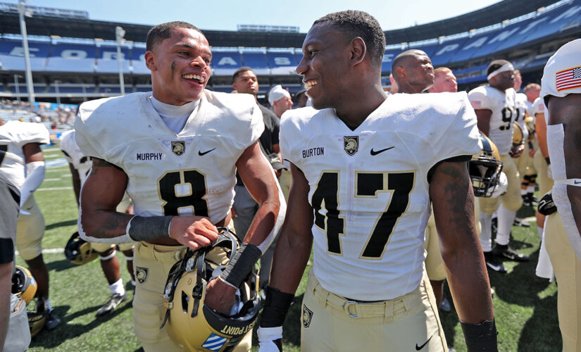 Army football players run out on field carrying American flags